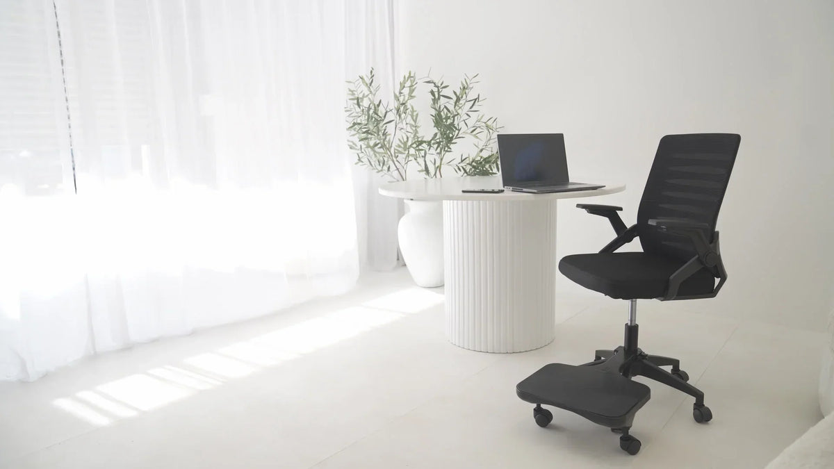 PostureAssist Foot Rest attached to a modern office chair in a bright workspace